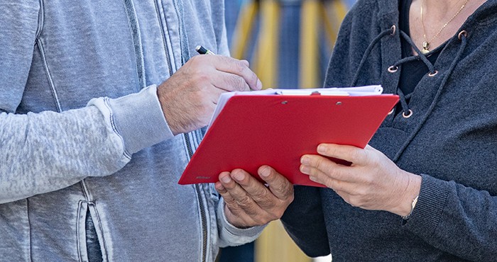 Two people pointing to a petitions form on clipboard.