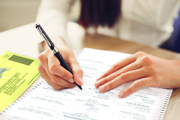 Cropped view of person holding pen and looking through document at desk